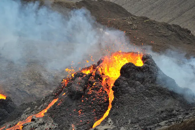 Das Bild zeigt einen ausbrechenden Vulkan mit fließender Lava und aufsteigenden Asche- und Gaswolken.