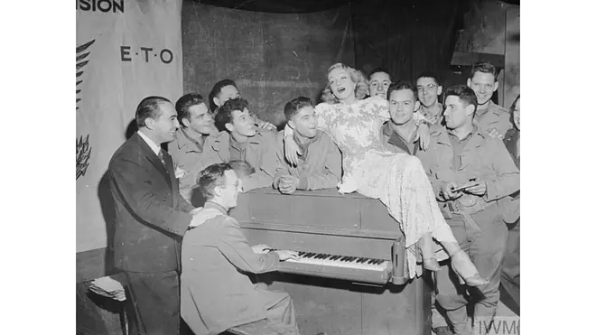 Schwarz/Weiß Fotografie einer Frau auf einem Piano umgeben von vielen Männern