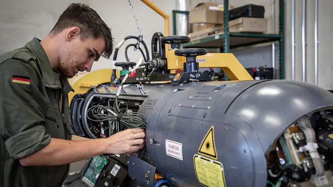 Ein Bild zeigt einen Ingenieur der Wehrtechnik bei der Prüfung eines Aufklärungssystems.