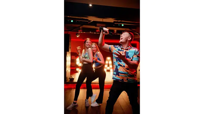 Freunde singen Karaoke bei ausgelassenem Abend.
