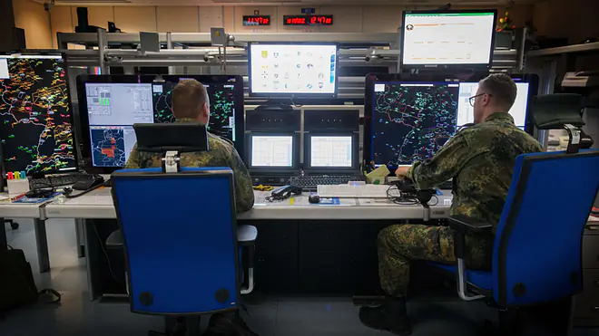 Ein Bild zeigt zwei Soldaten des Air Battle Management Service, die ein Luftlagebild im Control and Reporting Center erstellen.