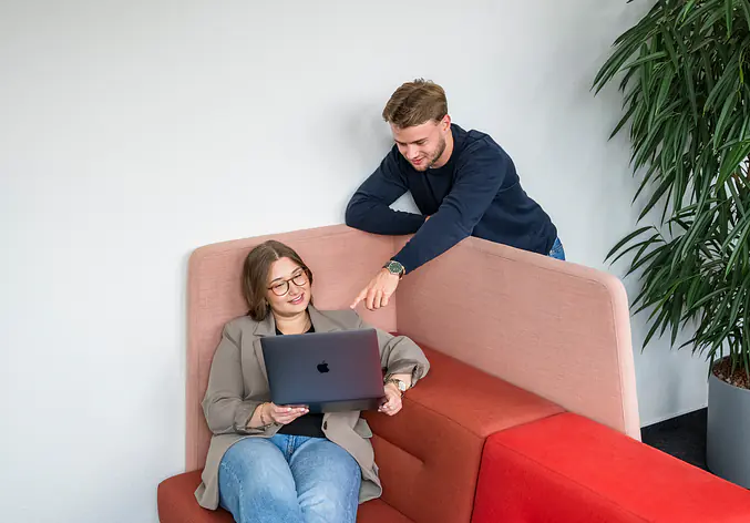 Auszubildende sitzen im Büro mit Laptop in der Hand