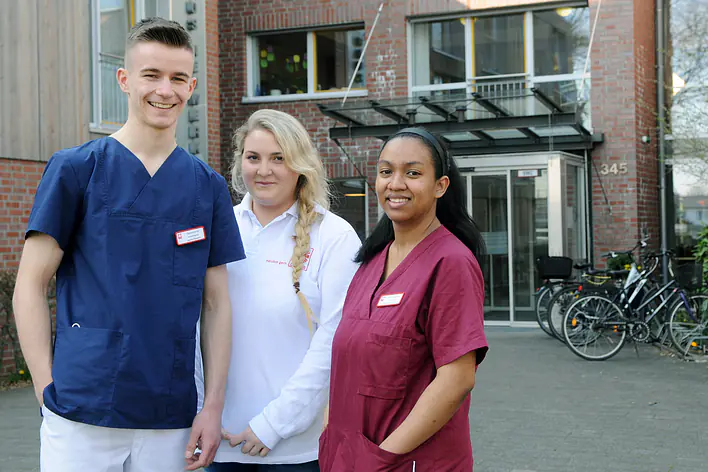 Auszubildende zu dritt vor Caritaszentrum