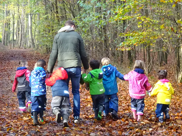 Eine Erzieherin mit sieben Kindern gehen durch den Wald