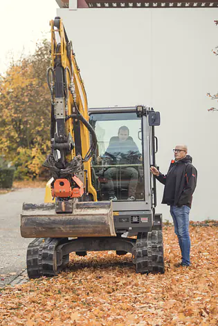 Student im Bagger, Professor steht rechts daneben