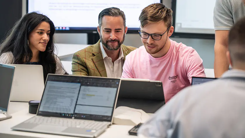 Studierende mit Dozent am Notebook