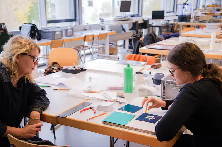 Studentin in einem Gespräch mit einer Professorin in der Modellbauwerkstatt