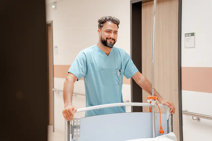 Eine Pflegekraft schiebt ein Bett.