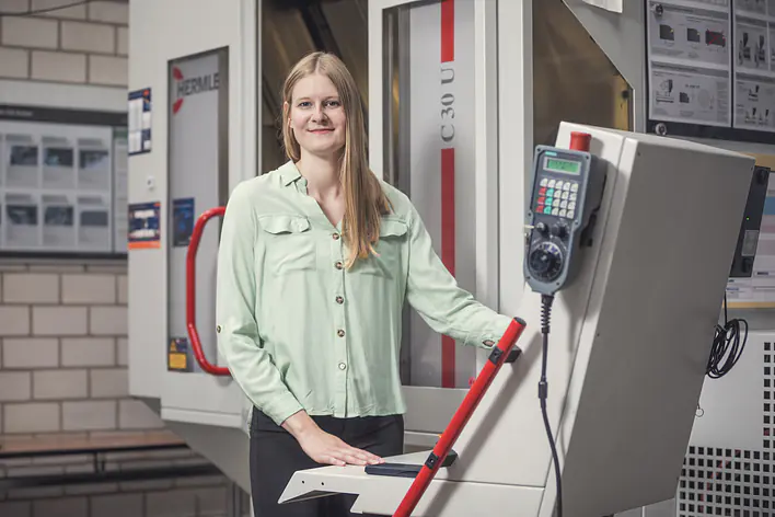 Studentin an einer Maschine in einer Laborhalle