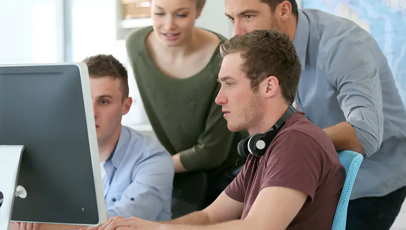 Studierende versammeln sich um einen Rechner