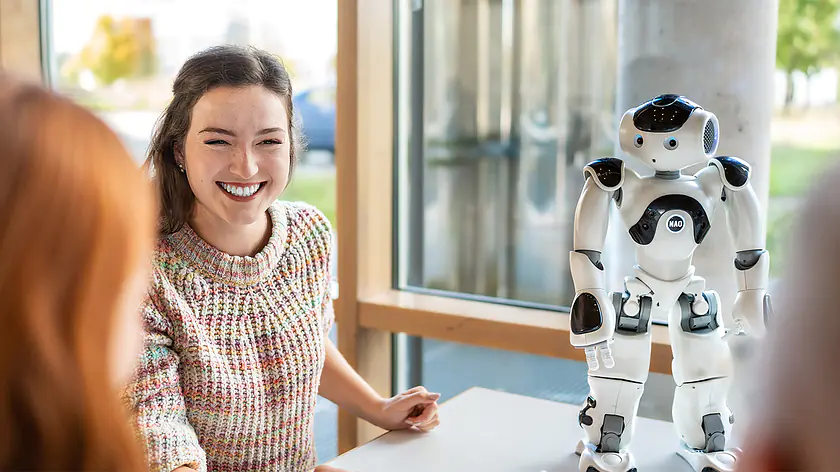 Studierende im Bereich Künstliche Intelligenz oder Robotik bei der Arbeit mit einem humanoiden Roboter am Campus