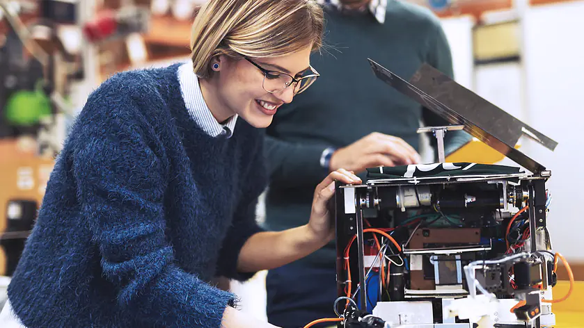 Praxisnahes Maschinenbau-Studium: Studierende bei der Montage und Feinjustierung eines Robotik-Prototyps in einem modernen Labor