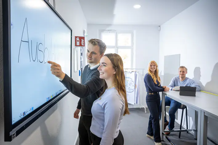 Zwei Personen, die an einem Wandpanel stehen.