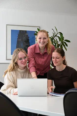 Drei junge Frauen am Schreibtisch vor dem Laptop